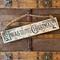A handmade Christmas sign. Old time writing has been wood-burned onto a piece of reclaimed wood. Reindeer and holly are on either side. 
